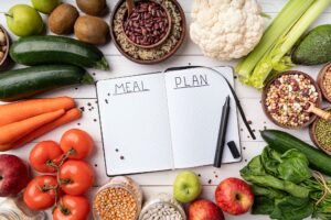 Weight lose and dieting concept. Notepad with words meal plan with healthy food, top view flat lay